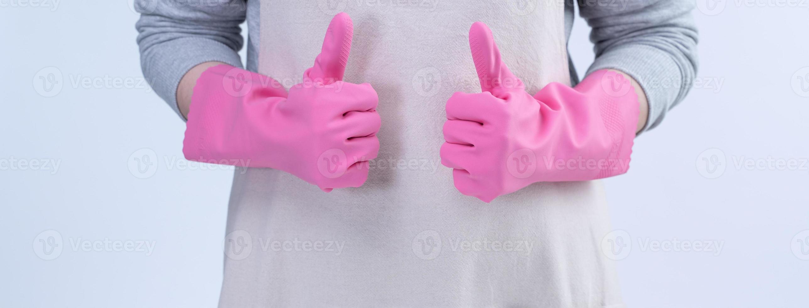 Young woman housekeeper in apron is wearing pink gloves to clean the table, concept of preventing virus infection, housekeeping service, close up. photo