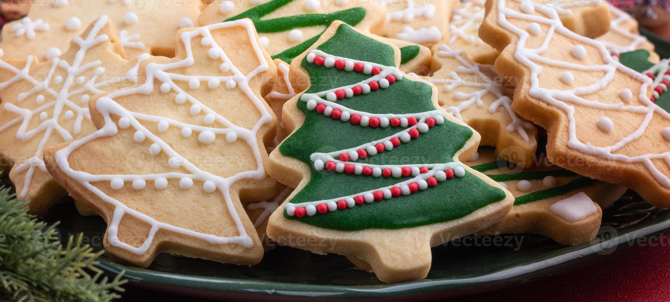 Close up of Christmas sugar cookies in a plate on red table background. photo