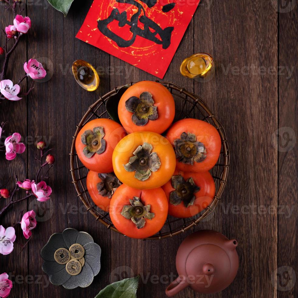 Top view of fresh sweet persimmons with leaves on wooden table background for Chinese lunar new year photo