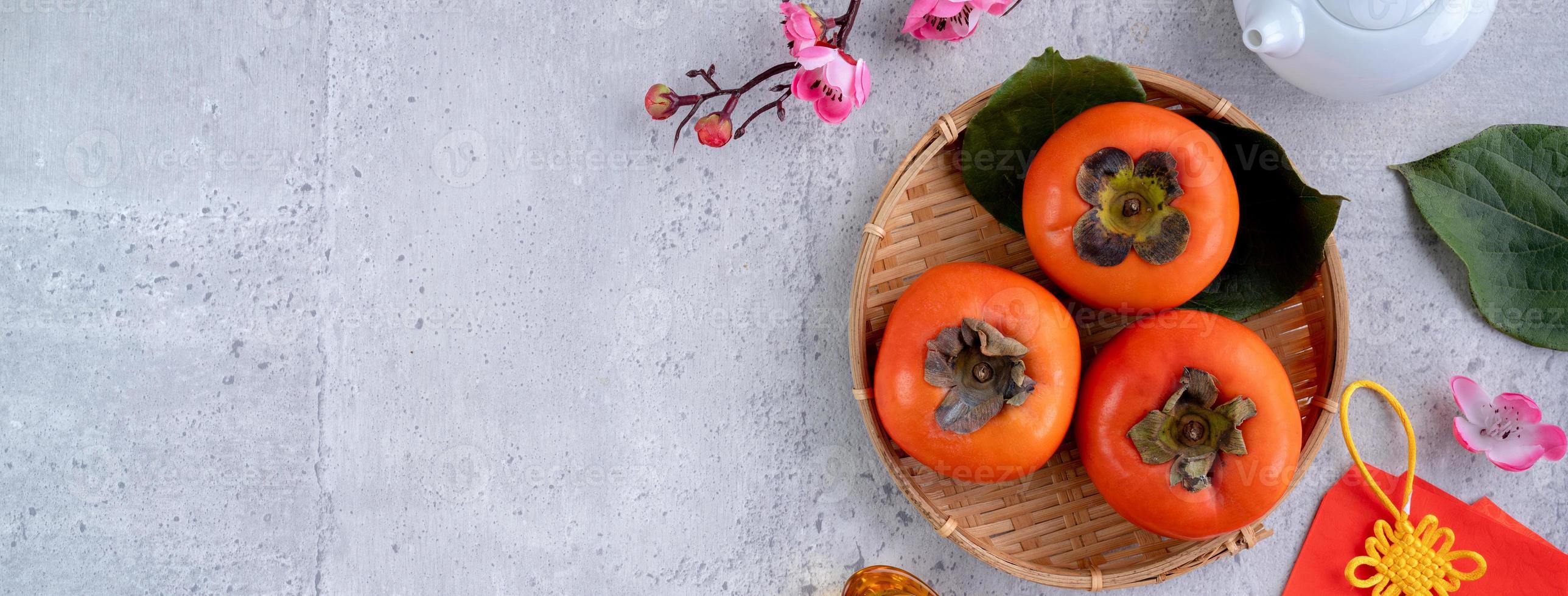 Top view of fresh sweet persimmons with leaves on gray table background for Chinese lunar new year photo