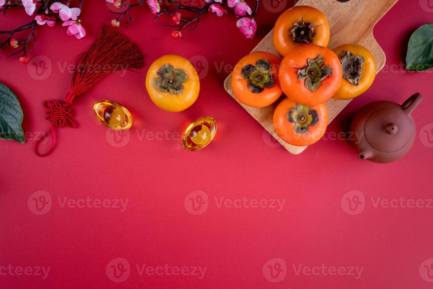 Top view of fresh sweet persimmons with leaves on red table background for Chinese lunar new year photo