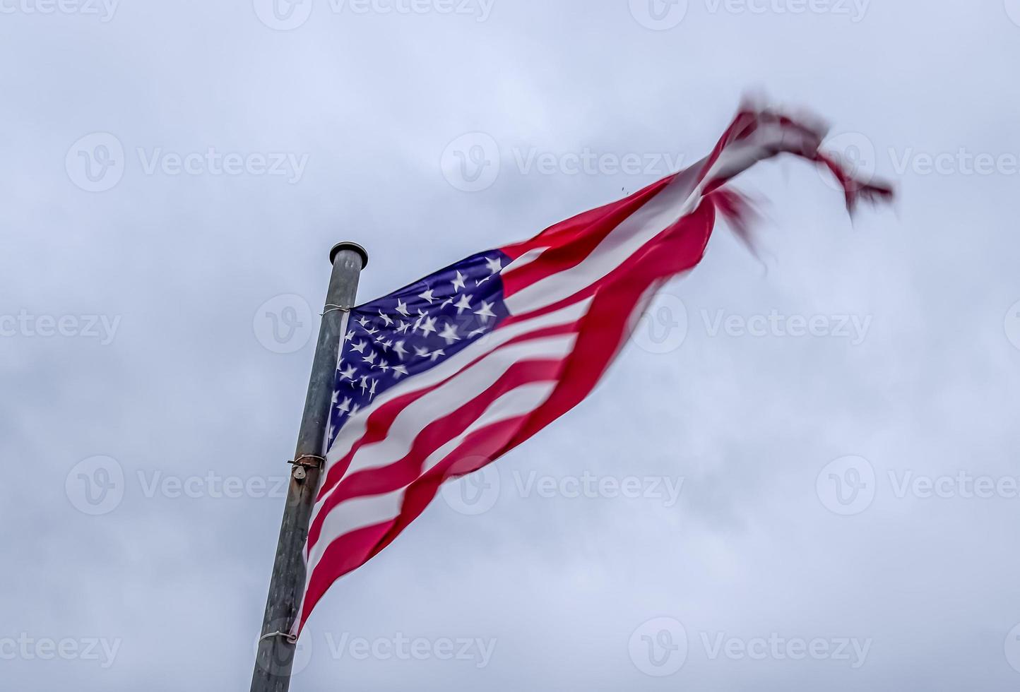 bandera de estados unidos en un asta de bandera moviéndose lentamente en el viento contra el cielo foto