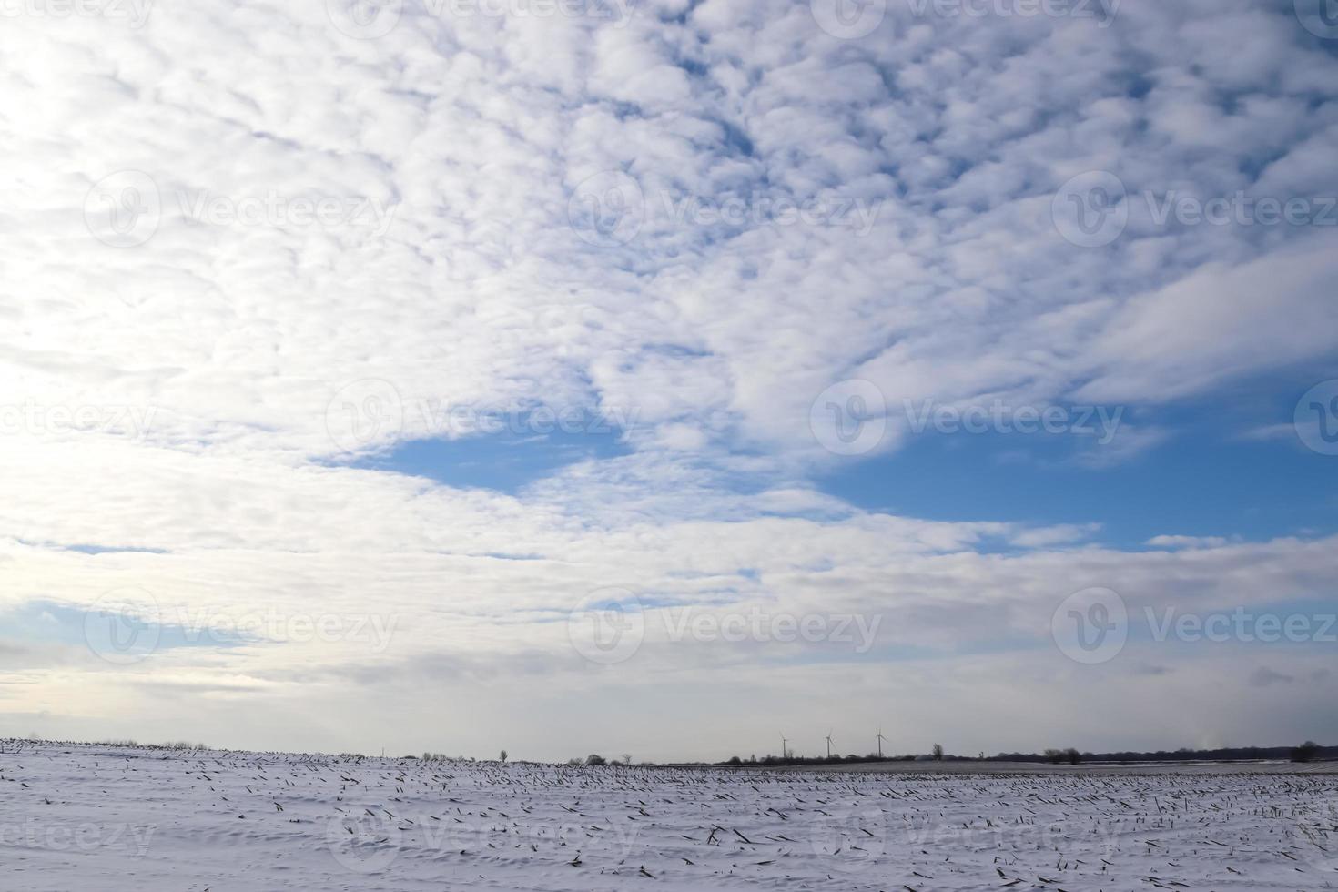 Beautiful clouds in the sky looking over a snow covered agricultural field. photo