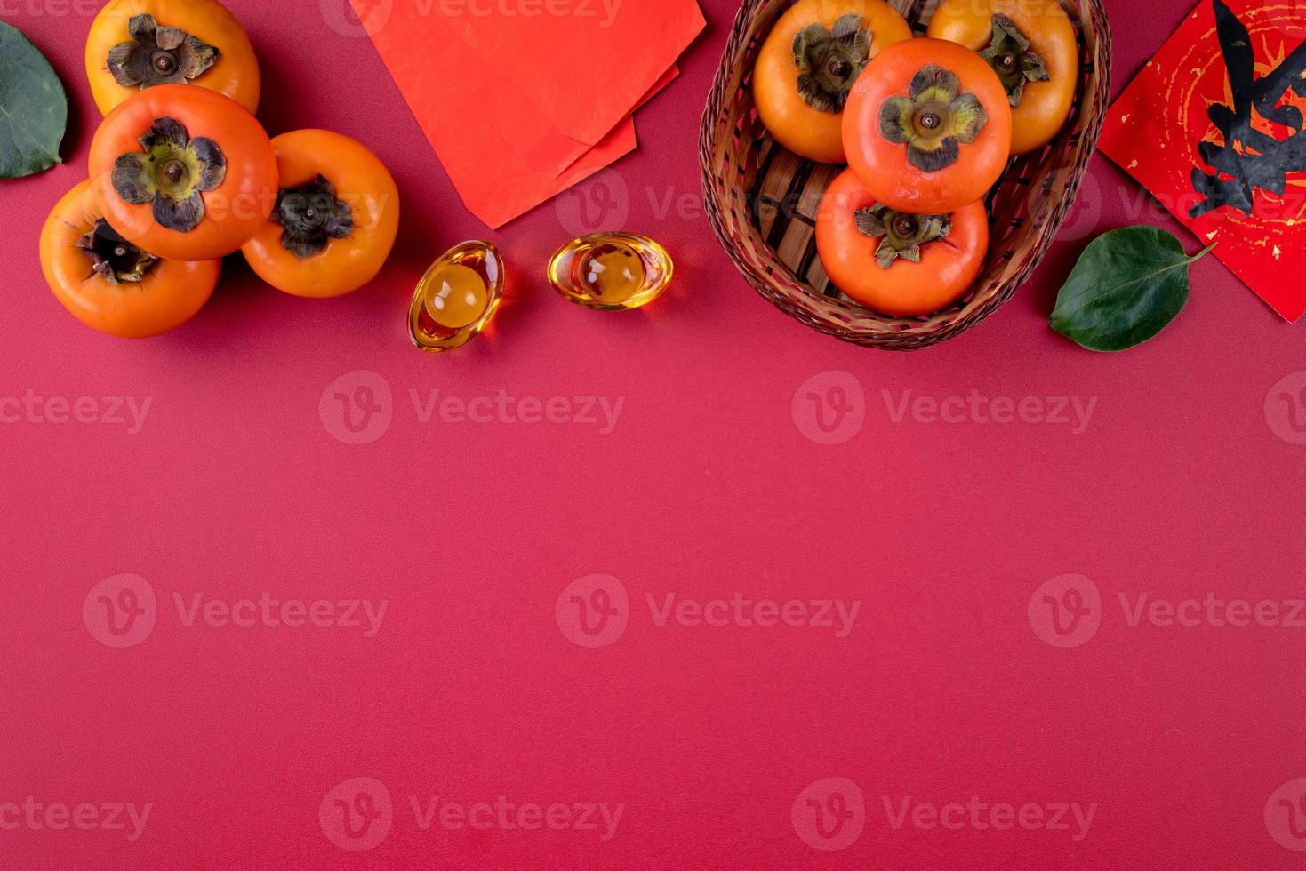 Top view of fresh sweet persimmons with leaves on red table background for Chinese lunar new year photo