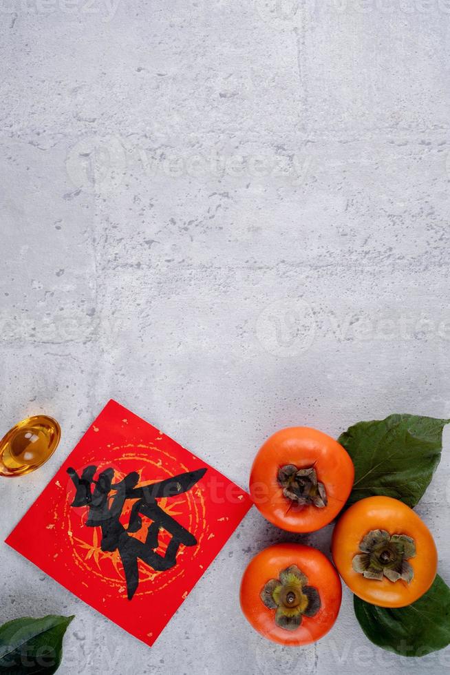 Top view of fresh sweet persimmons with leaves on gray table background for Chinese lunar new year photo