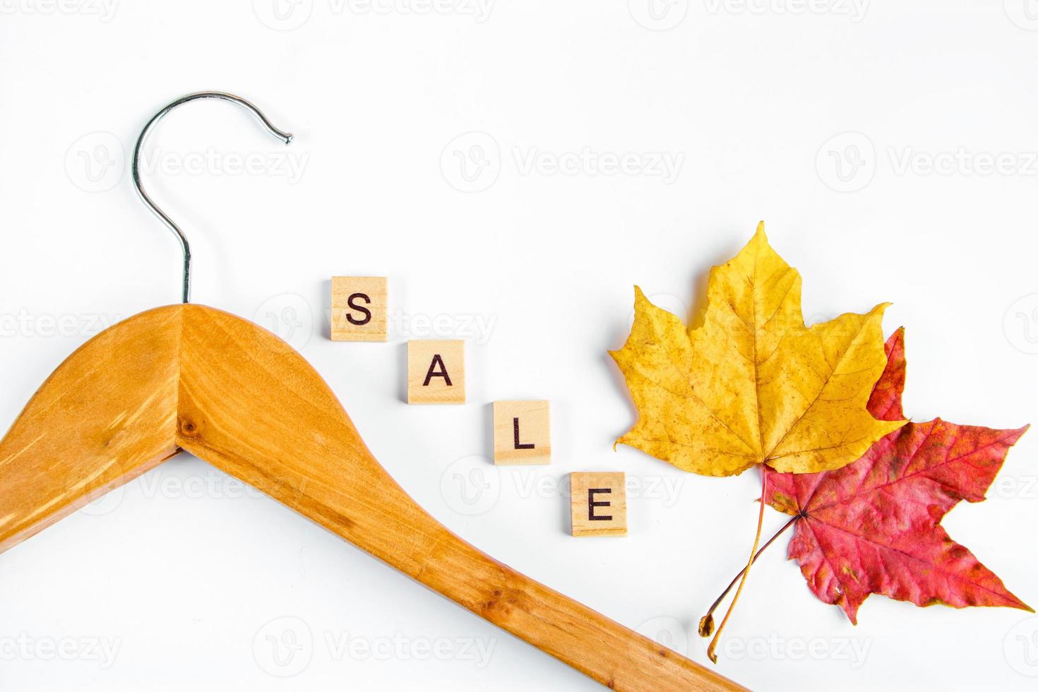 Autumn sale and discount. Clothes hanger, yellow leaves and blank labels on white background. Concept for advertising. photo