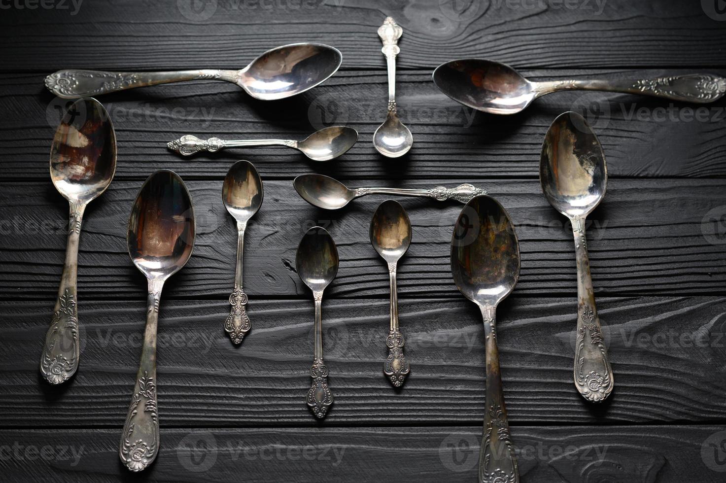 Directly above a shot of old spoons on a black table photo