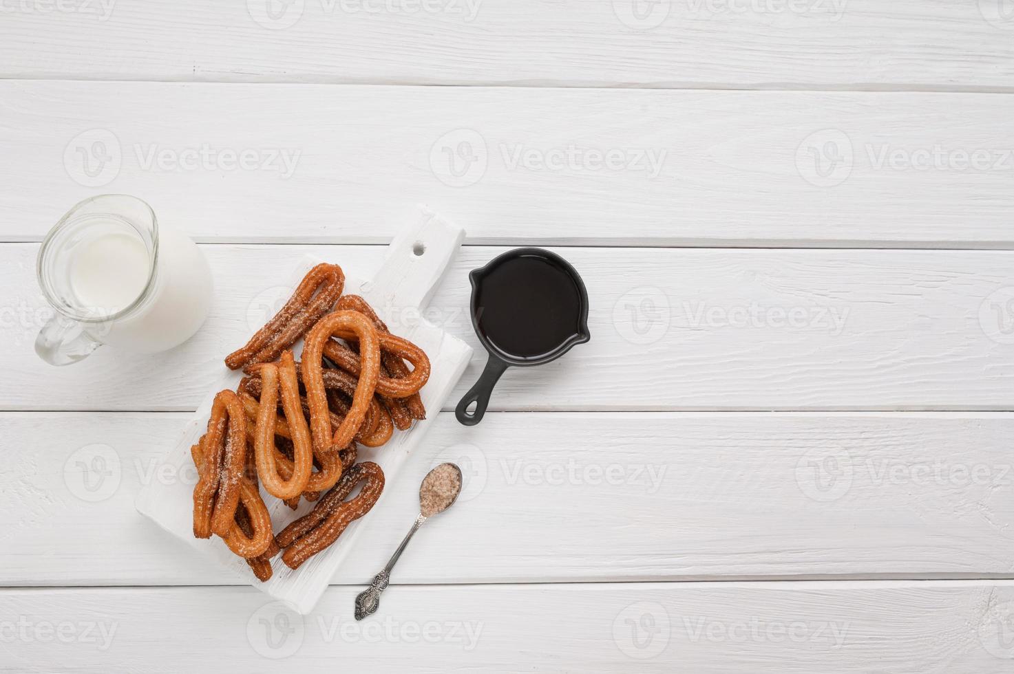 Homemade churros with chocolate on a white wooden background. photo