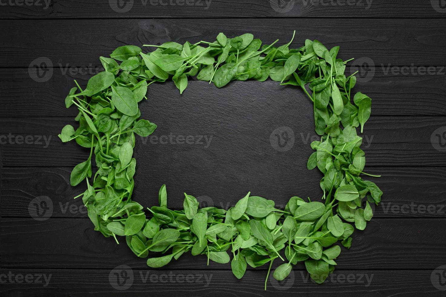 Kitchen table with stone cutting board, decorated with herbs. Presented on the black wooden background with center empty space. Table top view. photo