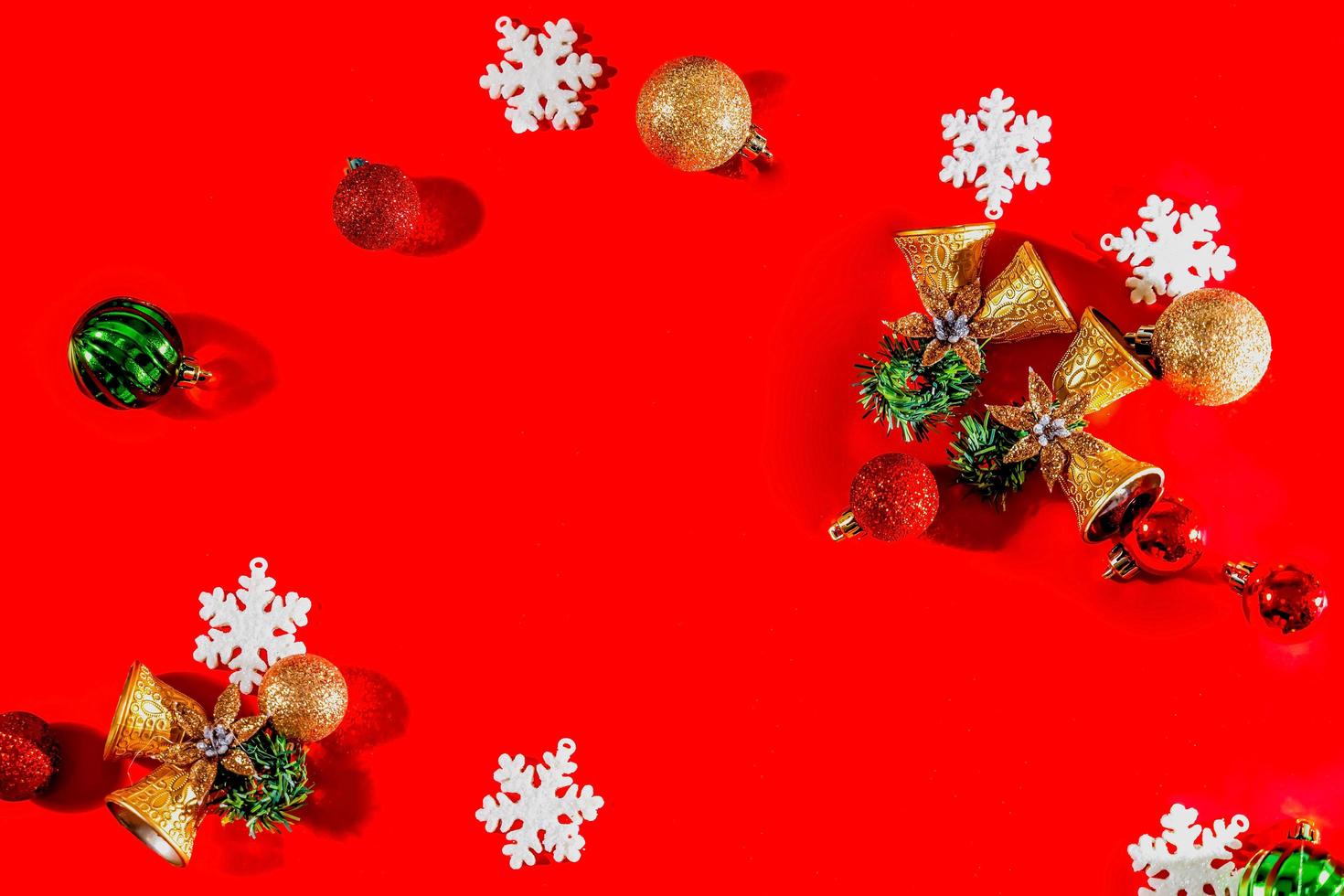 Christmas background concept. Top view of Christmas golden bells with balls decoration, spruce branches, star and snowflakes on red background. photo