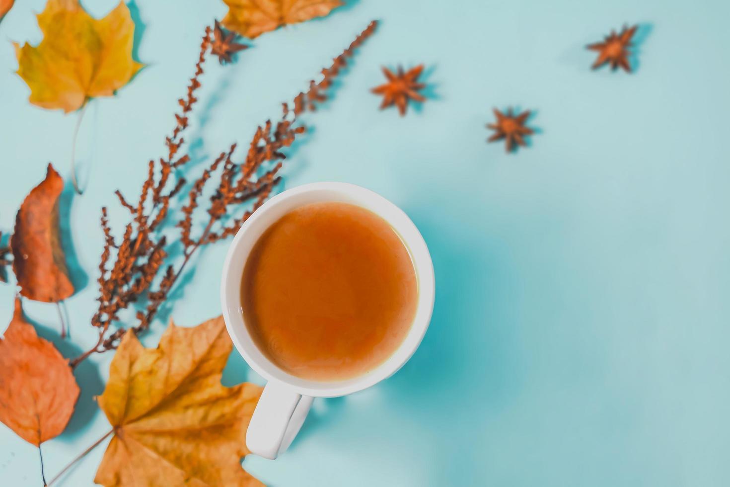 Autumn composition. Cup of coffee, autumn leaves , cinnamon sticks and anise stars on Bright Blue pastel  background. Flat lay, top view copy space. photo