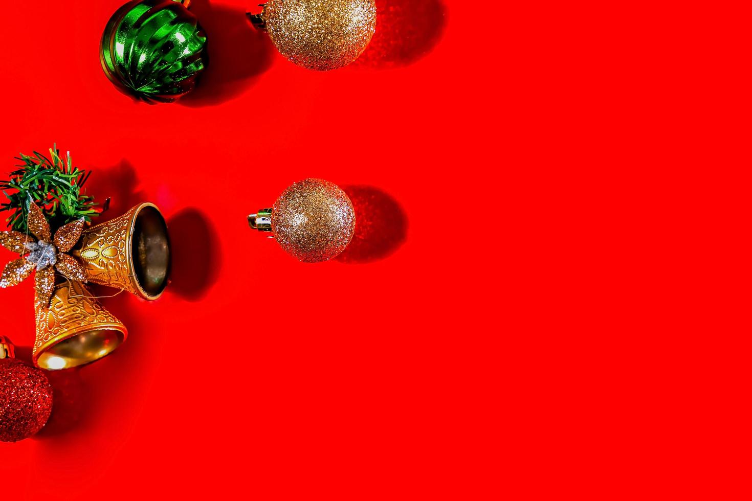 Christmas background concept. Top view of Christmas golden bells with balls decoration, spruce branches, star and snowflakes on red background. photo