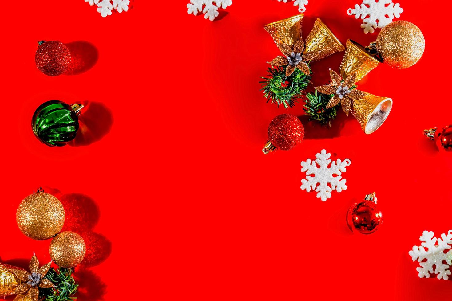 Christmas background concept. Top view of Christmas golden bells with balls decoration, spruce branches, star and snowflakes on red background. photo