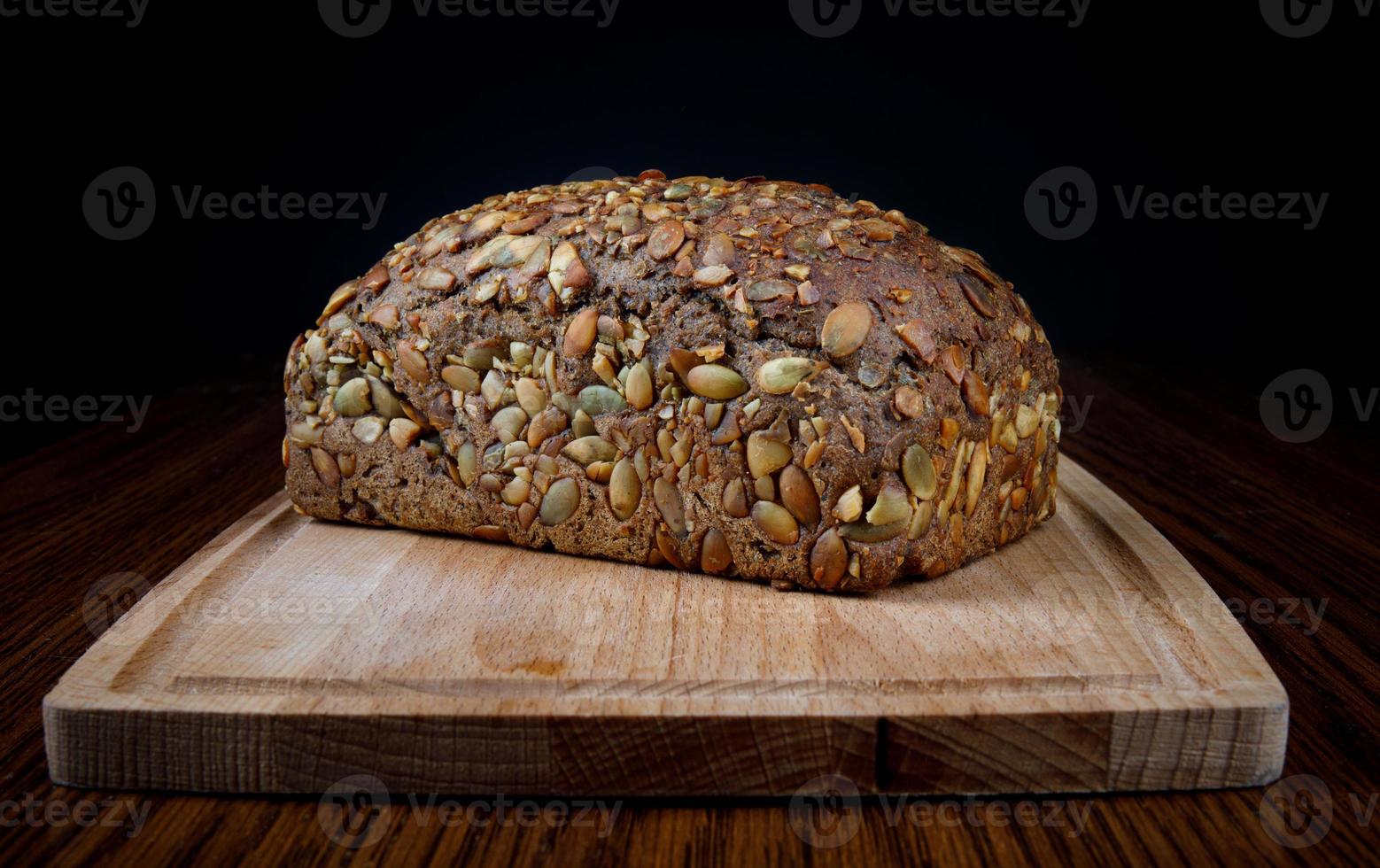 A bread bun with pumpkin seeds on a wooden board. photo