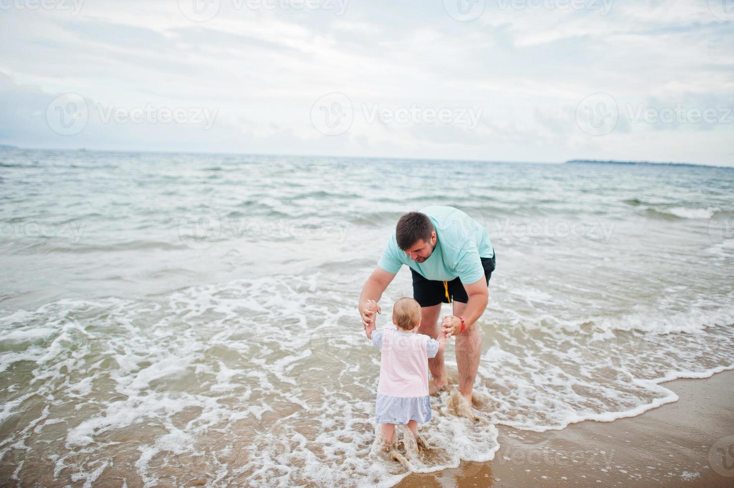 Summer vacations. Parents and people outdoor activity with children. Happy family holidays. Father with baby daughter on sea sand beach. photo