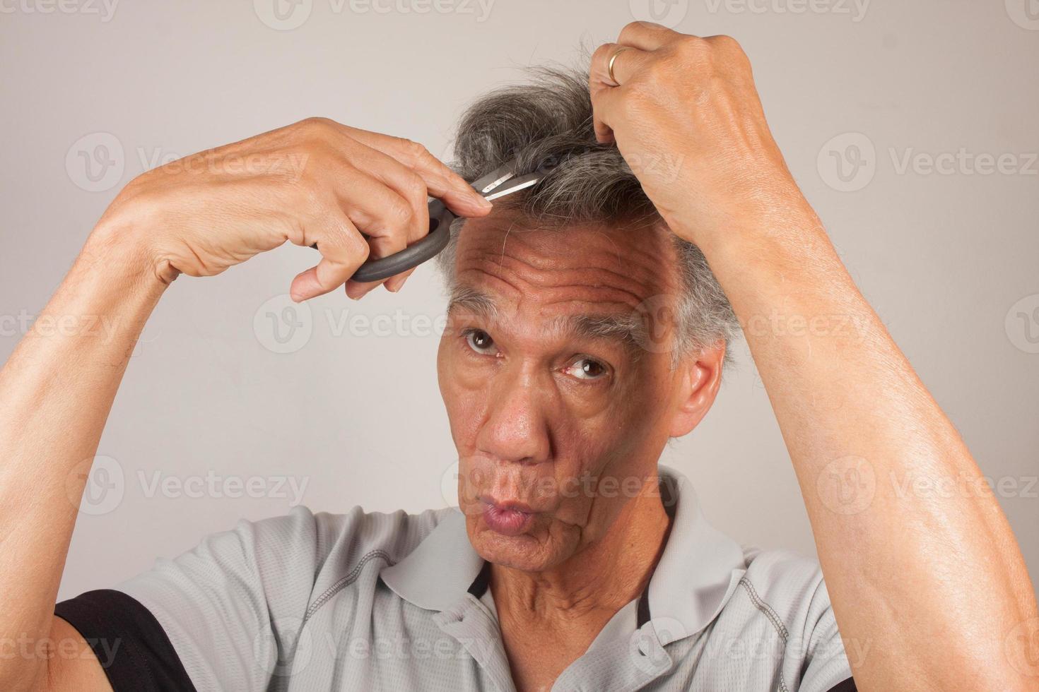 Mature Man trying to cut his own Hair with a Pair of Scissors photo