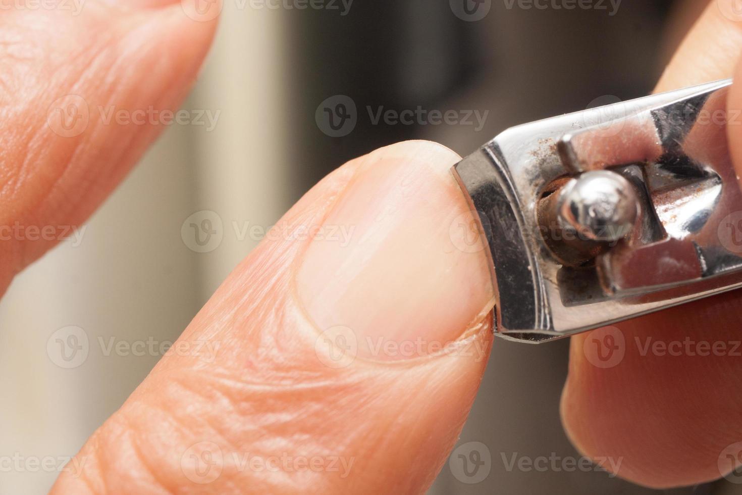 Man trimming his fingernails with a pair of nail trimmers photo