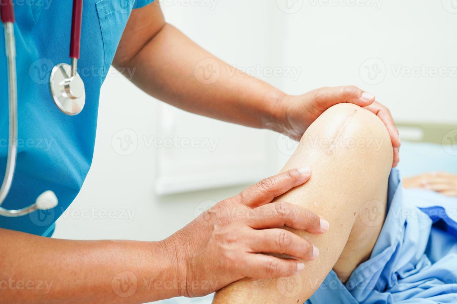 Doctor checking Asian elderly woman patient with scar knee replacement surgery in hospital. photo