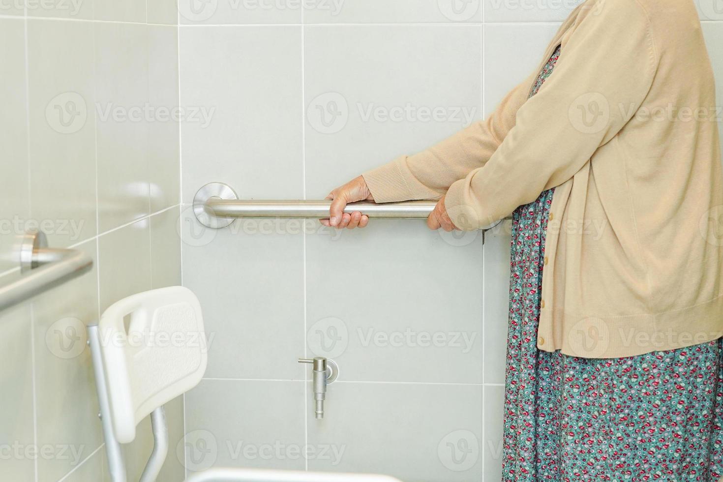 Asian elderly old woman patient use toilet support rail in bathroom, handrail safety grab bar, security in nursing hospital. photo