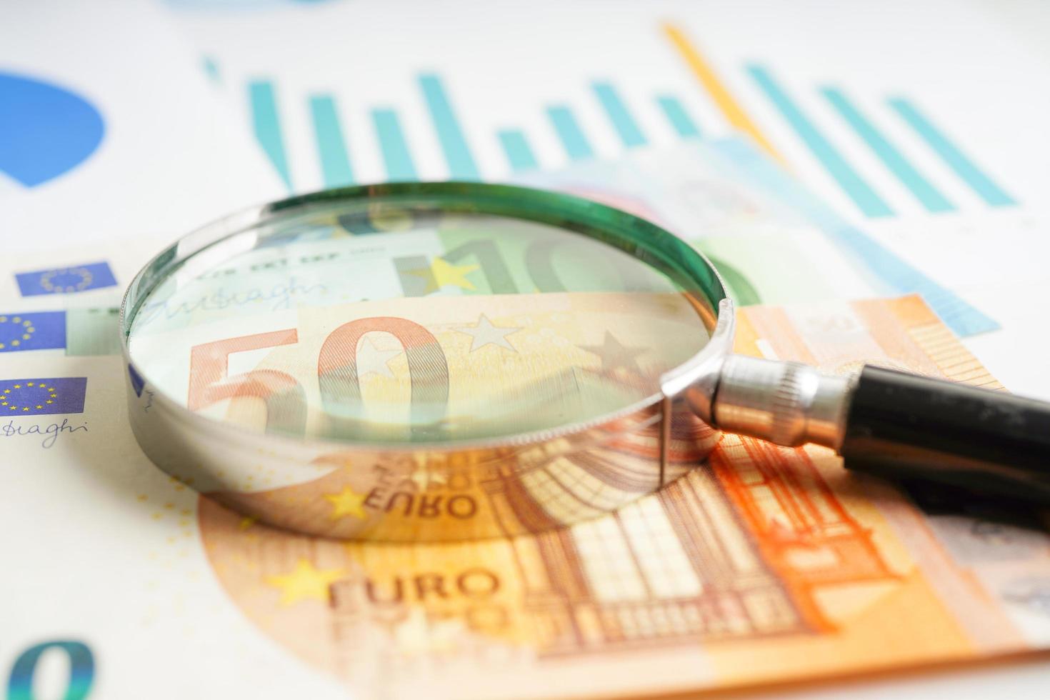 Magnifying glass on US dollar and EURO banknotes and graph, finance business trade concept. photo