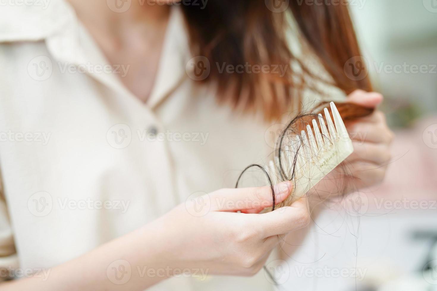 Asian woman have problem with long hair loss attach to comb brush. photo