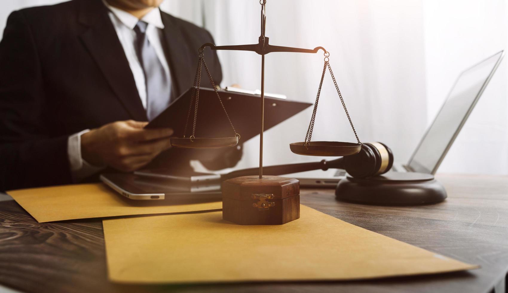 Justice and law concept.Male judge in a courtroom with the gavel, working with, computer and docking keyboard, eyeglasses, on table in morning light photo