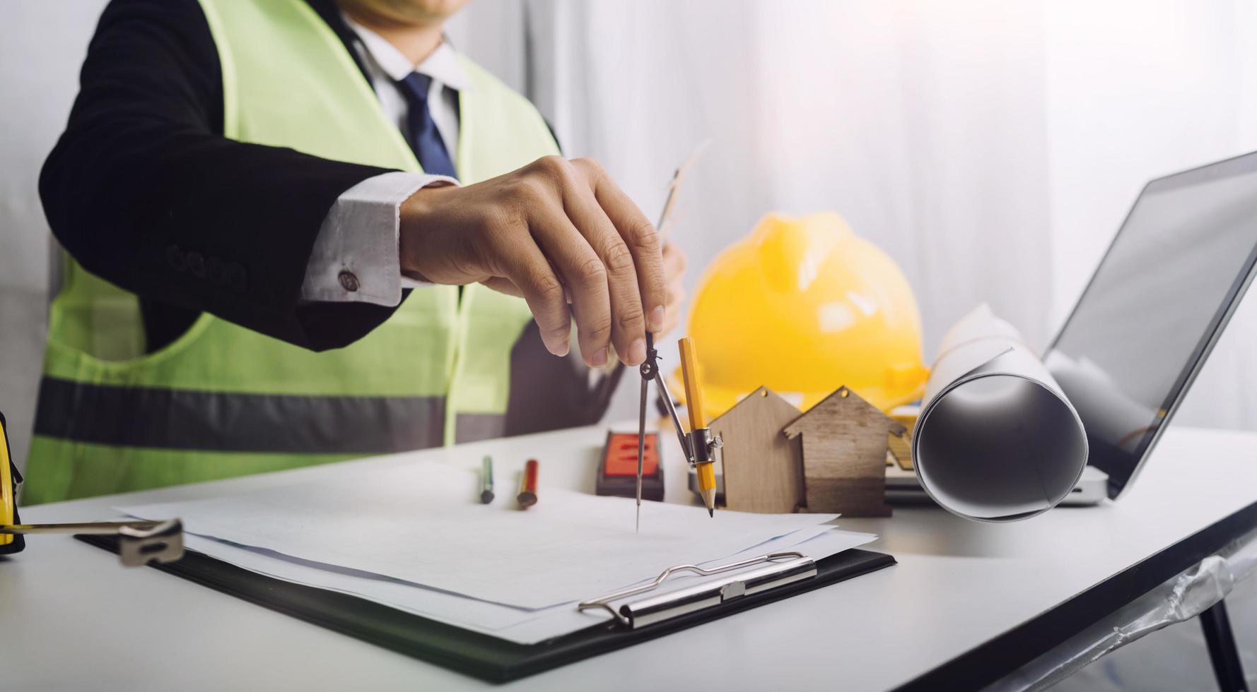 Two colleagues discussing data working and tablet, laptop with on on architectural project at construction site at desk in office photo