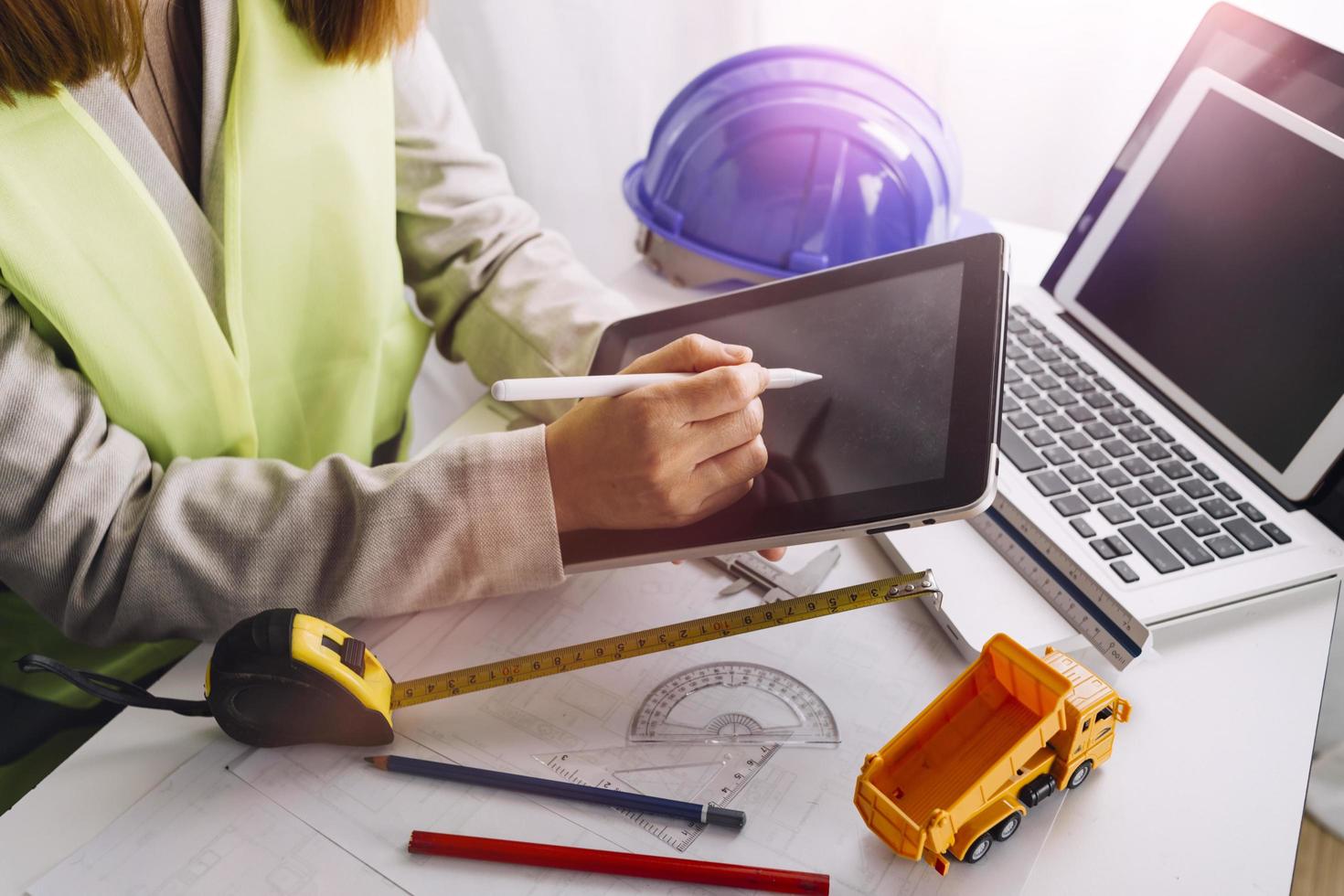 Two colleagues discussing data working and tablet, laptop with on on architectural project at construction site at desk in office photo