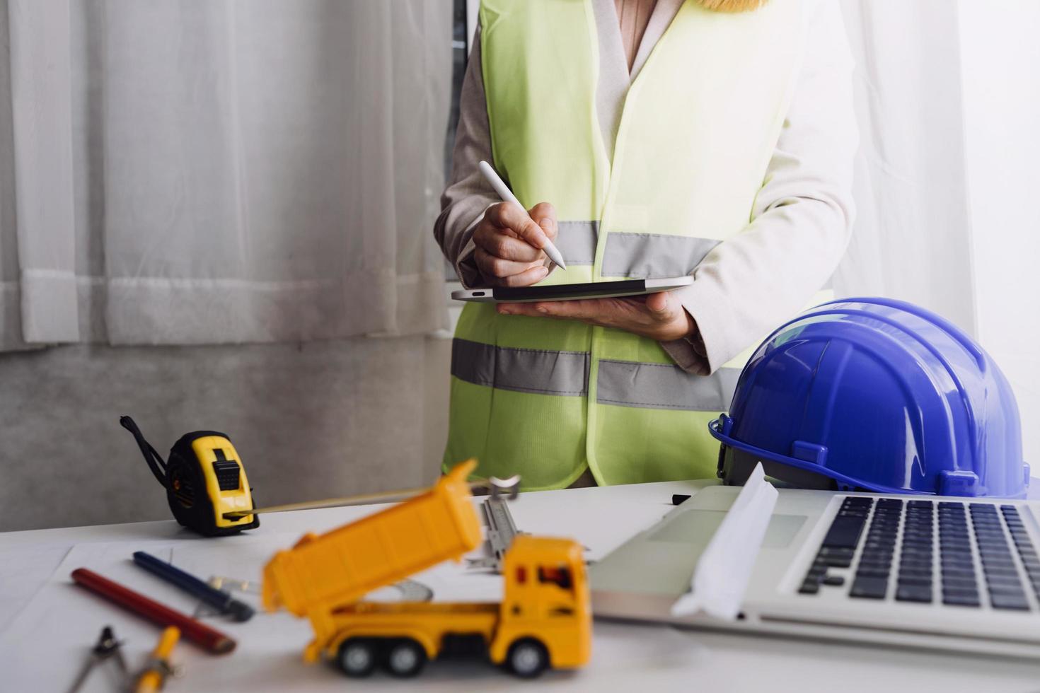 Two colleagues discussing data working and tablet, laptop with on on architectural project at construction site at desk in office photo