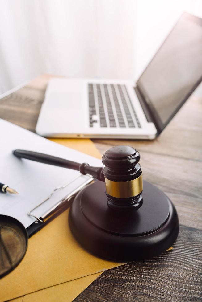 Justice and law concept.Male judge in a courtroom with the gavel, working with, computer and docking keyboard, eyeglasses, on table in morning light photo