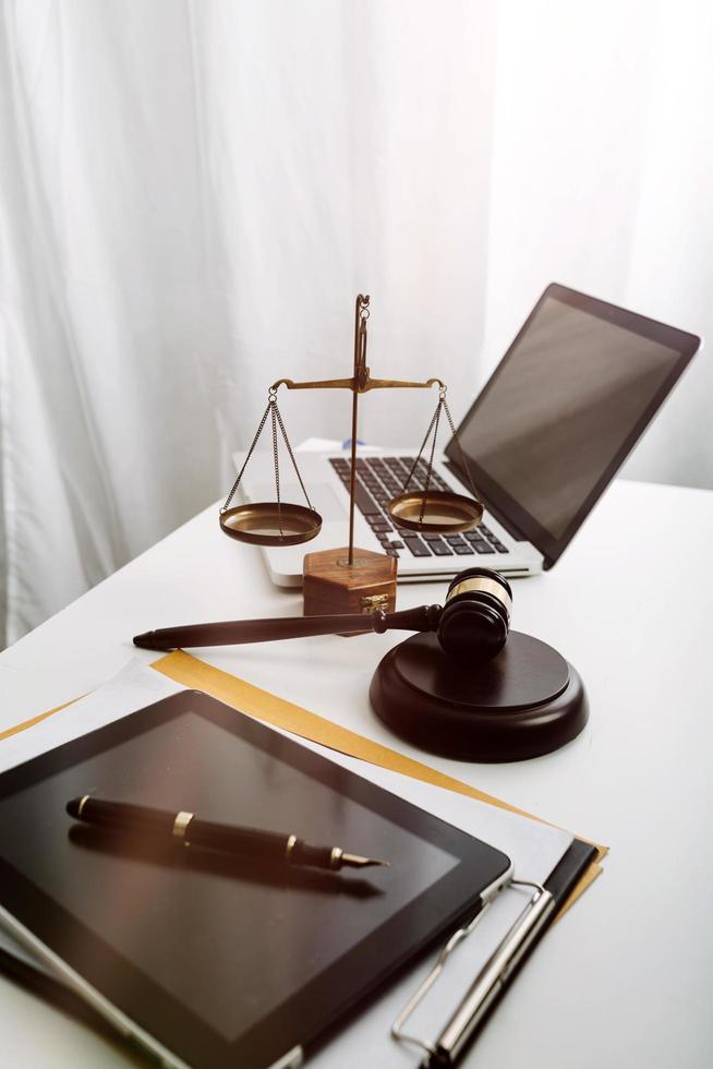 Justice and law concept.Male judge in a courtroom with the gavel, working with, computer and docking keyboard, eyeglasses, on table in morning light photo