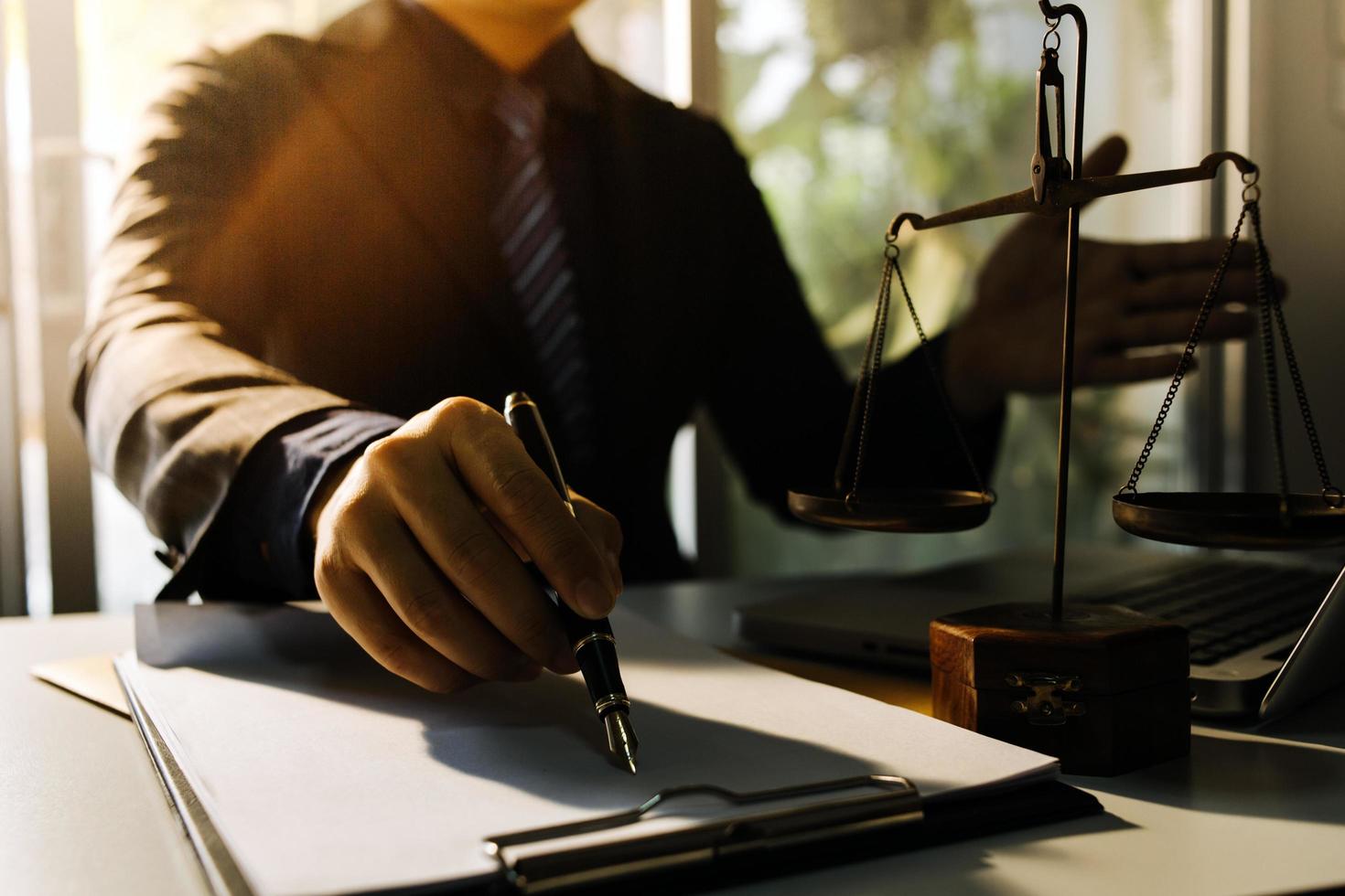 Business and lawyers discussing contract papers with brass scale on desk in office. Law, legal services, advice, justice and law concept picture with film grain effect photo