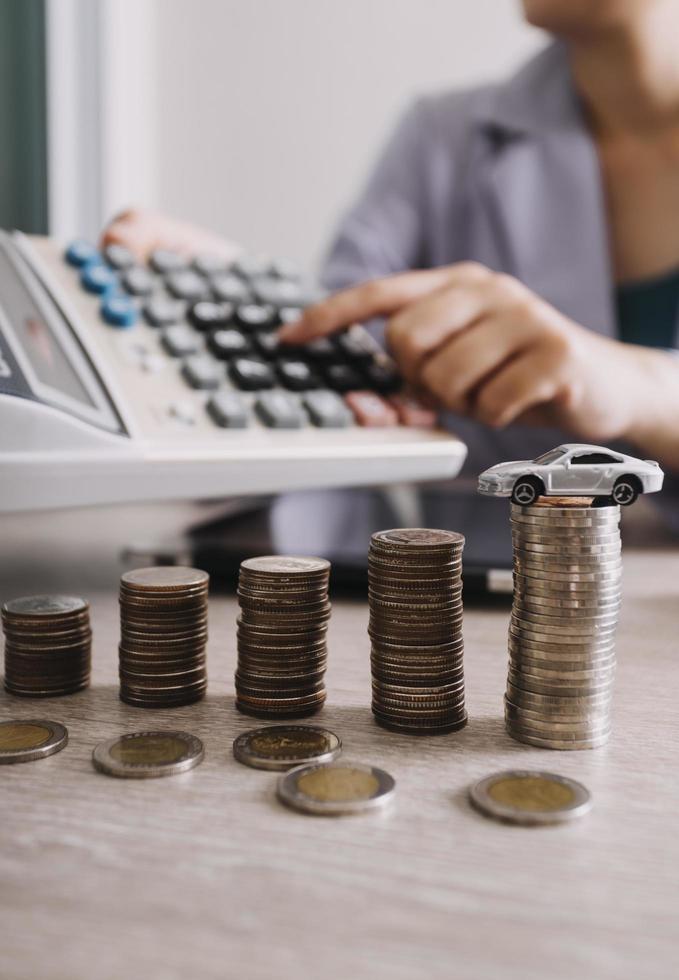 Close up of hand putting coin on pile coins for saving money. Collect money to buy a new car, saving and car loan concept. Flat lay photo