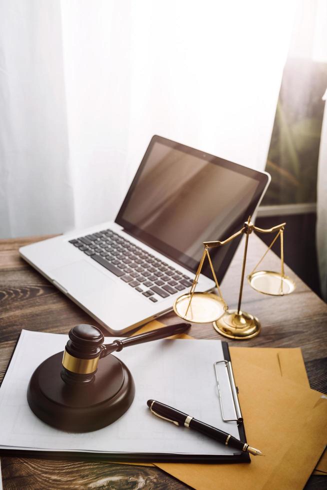 Justice and law concept.Male judge in a courtroom with the gavel, working with, computer and docking keyboard, eyeglasses, on table in morning light photo