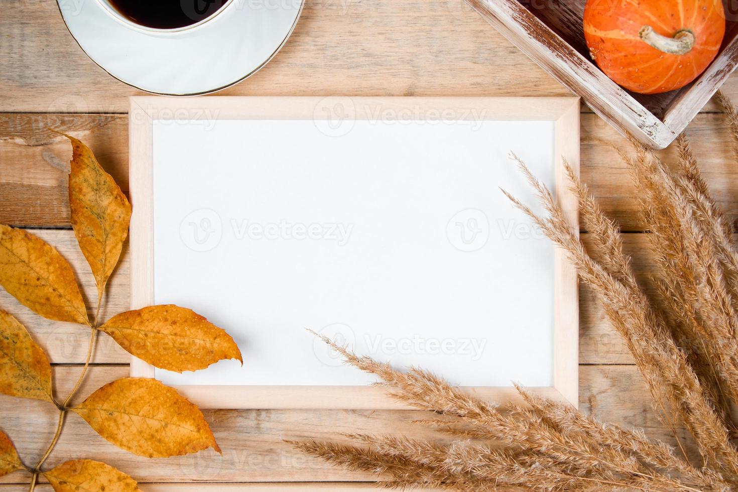Autumn flat lay. Cup of hot espresso coffee and fallen yellow leaves on wooden background. Empty frame mock up for text. Morning concept. photo