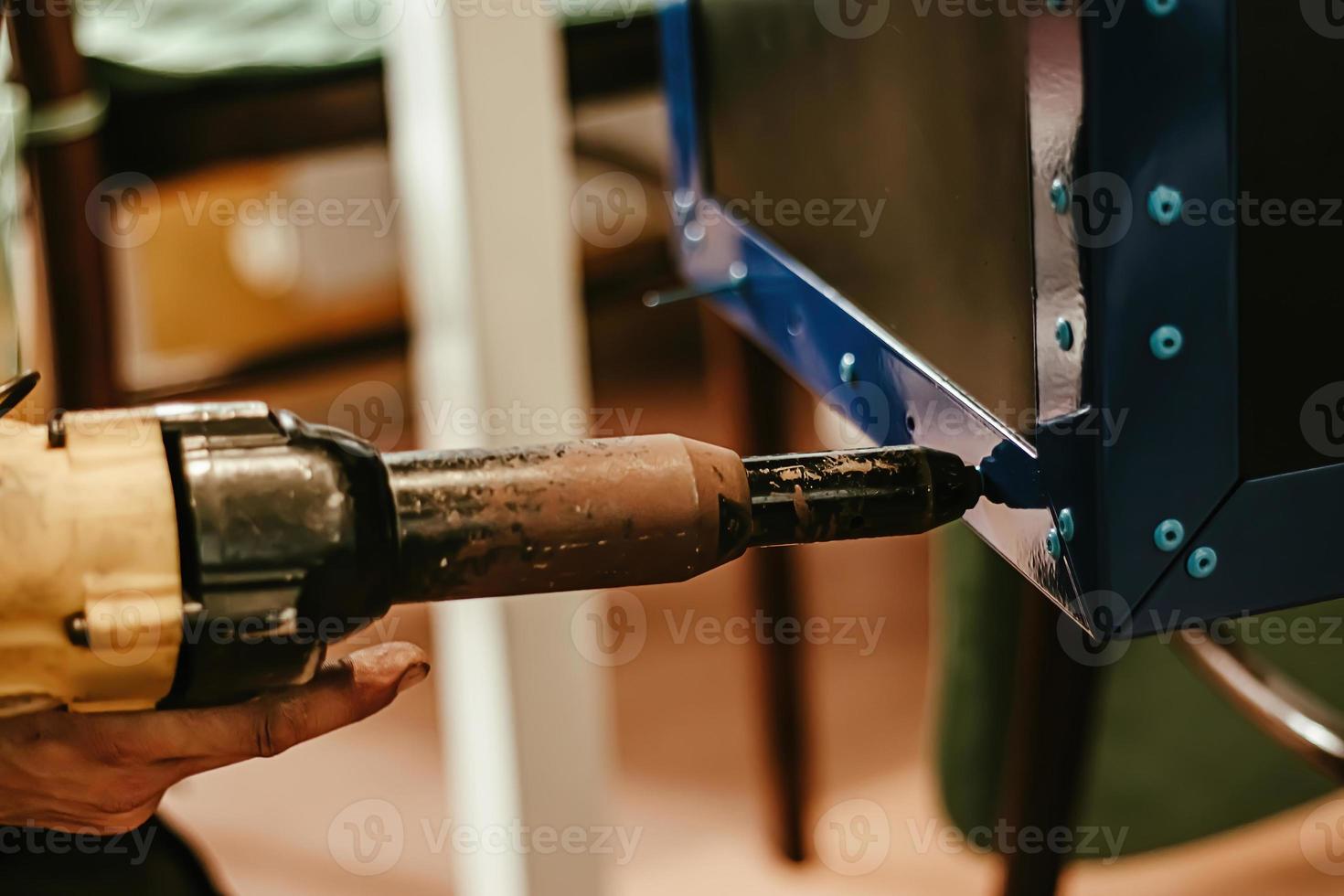 Male worker uses electric riveting gun. Hand holding  riveting m photo