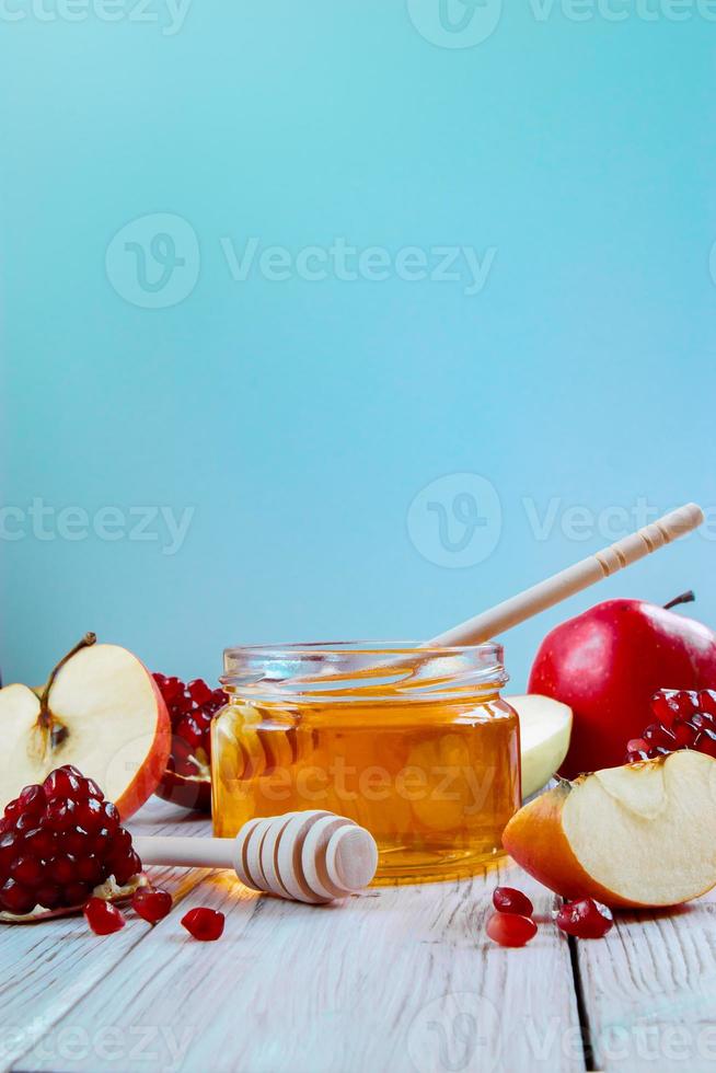 Happy Rosh Hashanah. Jar with honey, apples and pomegranates on blue background. Jewish traditional religious holiday. photo
