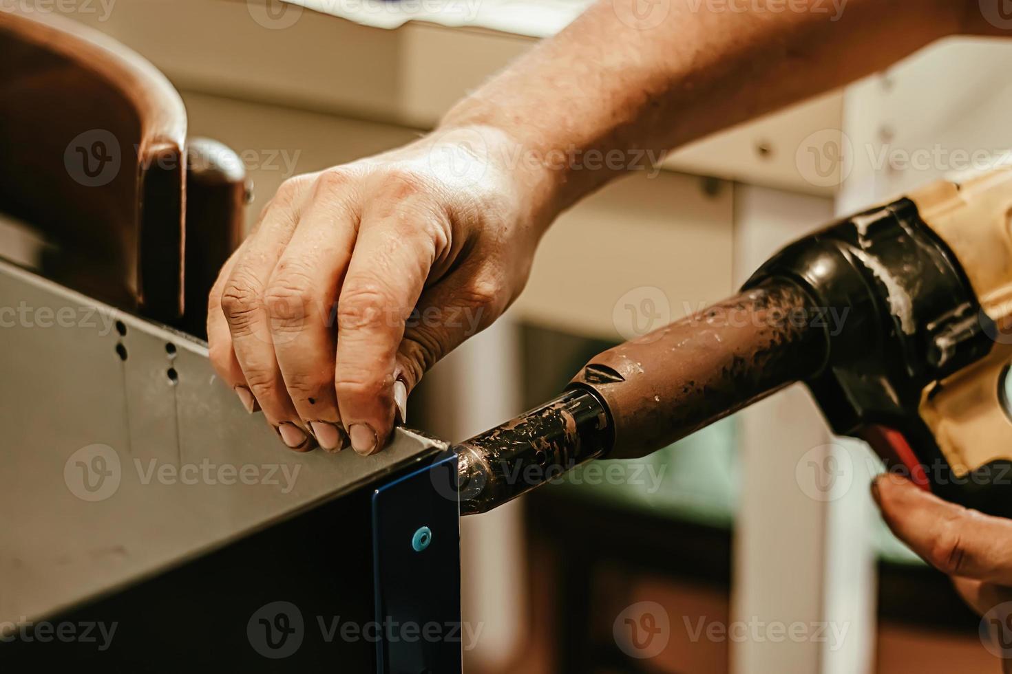 Male worker uses electric riveting gun. Hand holding riveting m photo