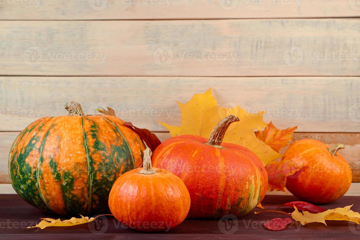 Autumn harvest. Ripe pumpkins and fallen leaves on wooden background. Thanksgiving and halloween concept. photo