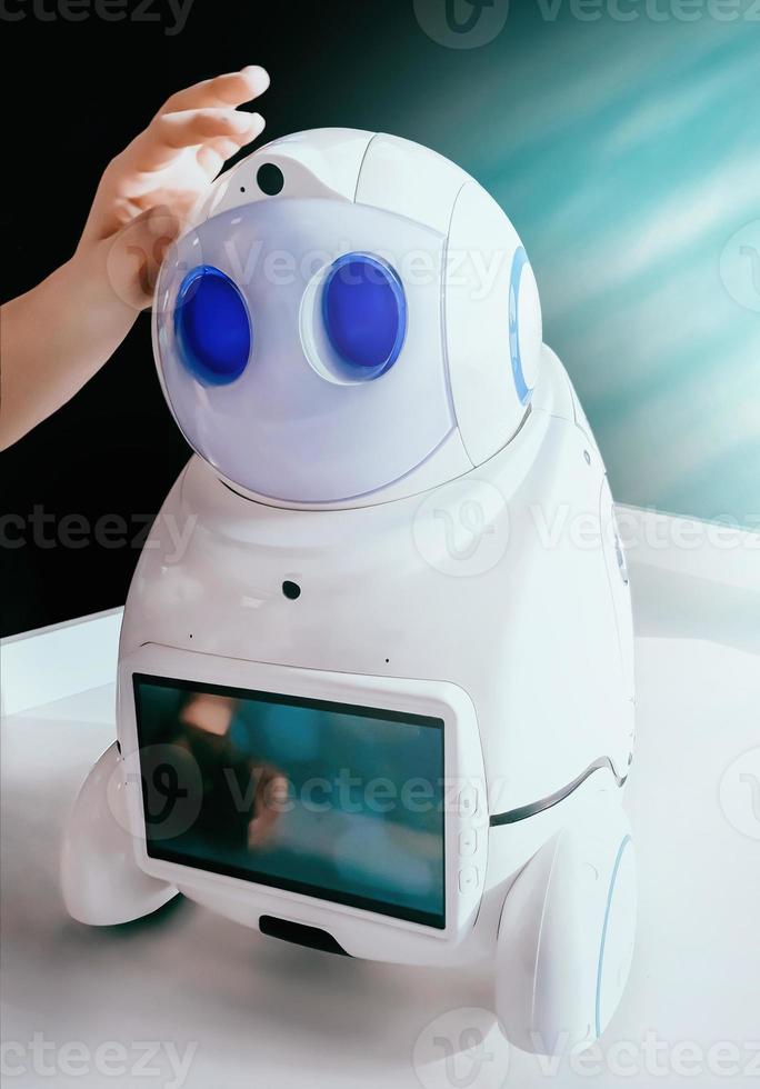 Interaction with AI robot. Technology development concept. Hand touches cute robot. photo