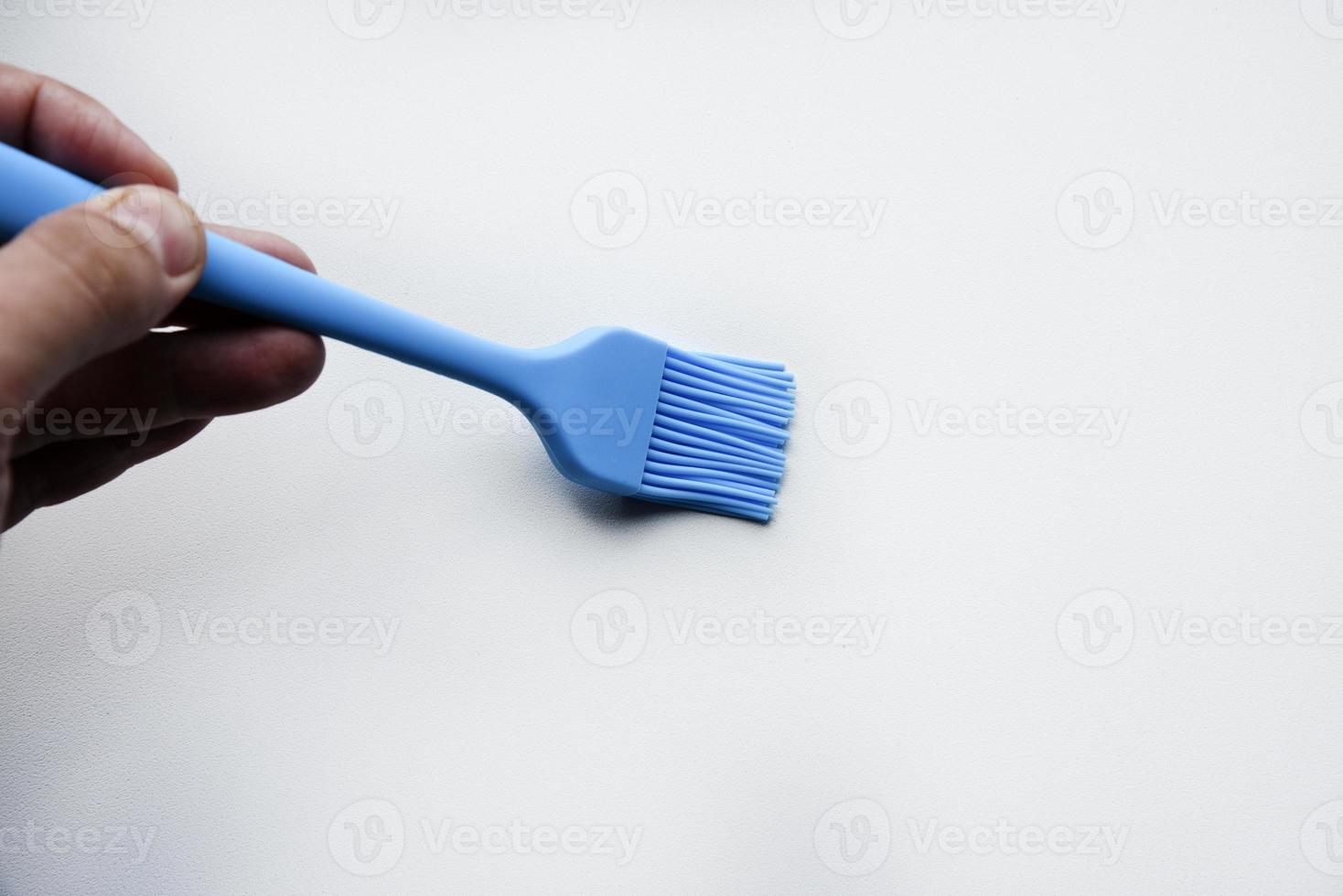 Blue plastic brush for smearing sunflower oil on a frying pan. A device for smearing oil. photo