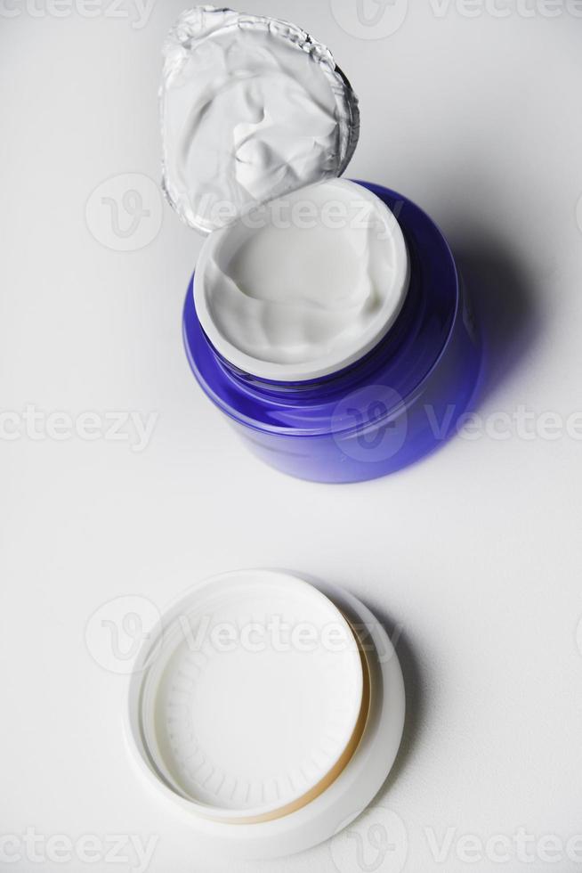 un frasco de crema facial sobre un fondo blanco. crema de noche y primer plano de manos. foto