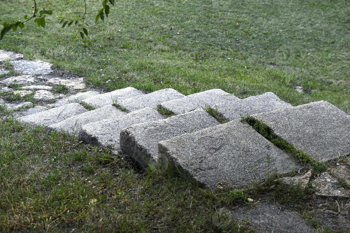 A stone path in the park and a granite staircase with steps. Stone steps in the garden. photo