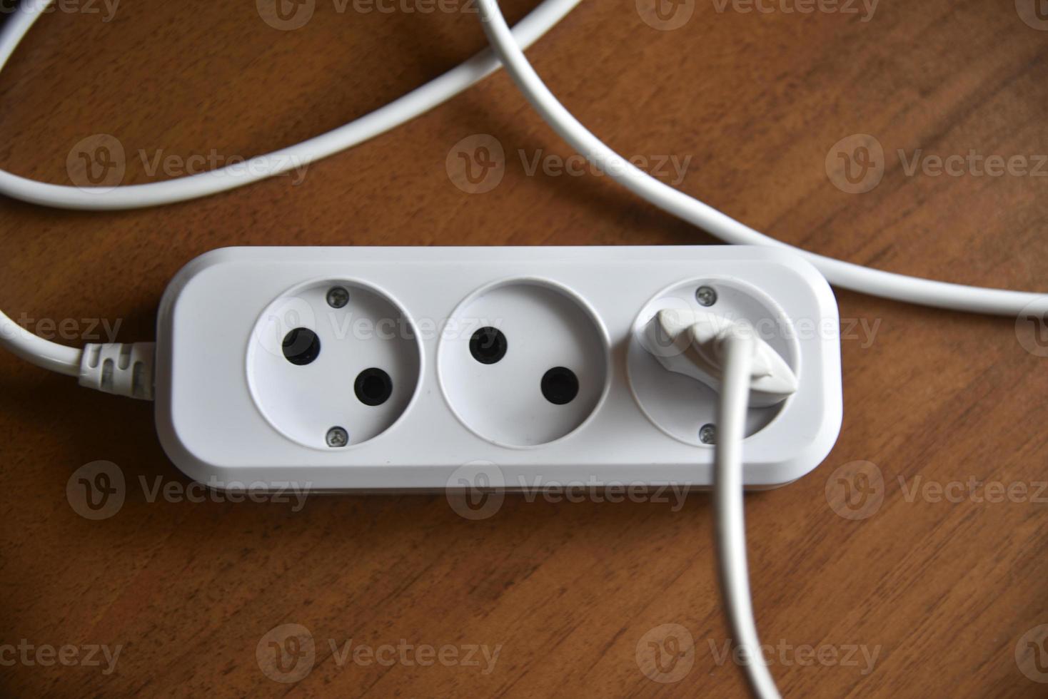 White electric extension cord on a wooden background photo