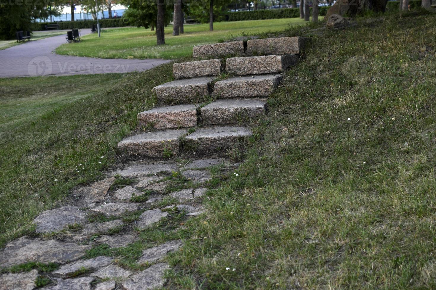 A stone path in the park and a granite staircase with steps. Stone steps in the garden. photo