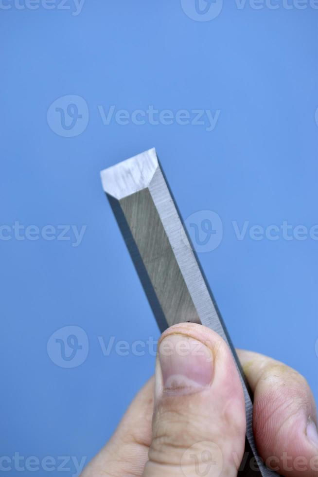 Steel chisel on wood in the hands. Carpentry iron hand tools. photo