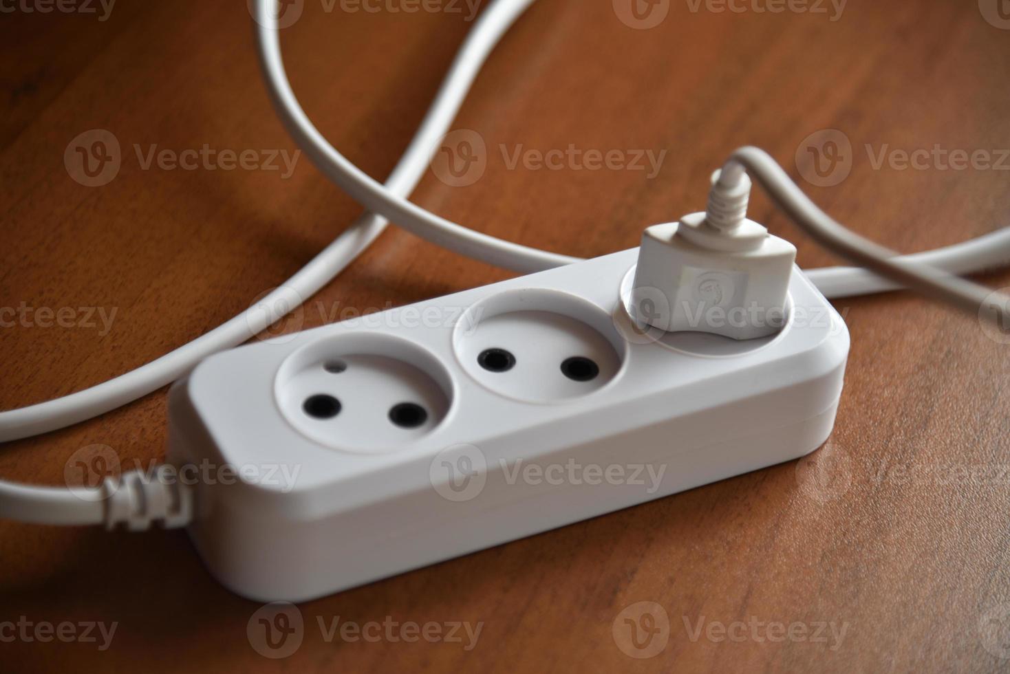 White electric extension cord on a wooden background photo