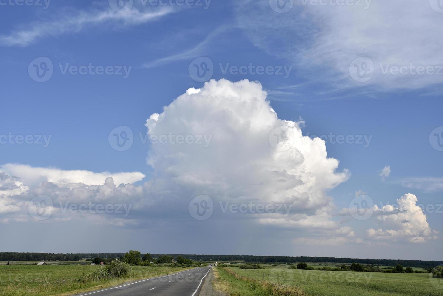 Thunderclouds on a summer day and a road in the countryside. A thunderstorm on a bright day. photo