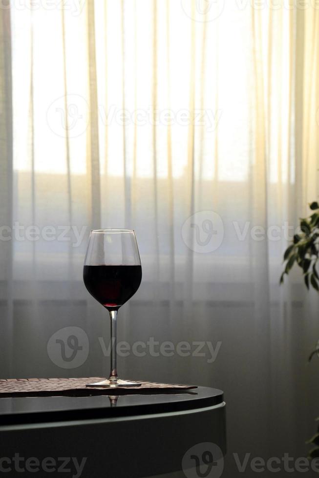 copa de vino tinto en la mesa mientras se pone el sol foto