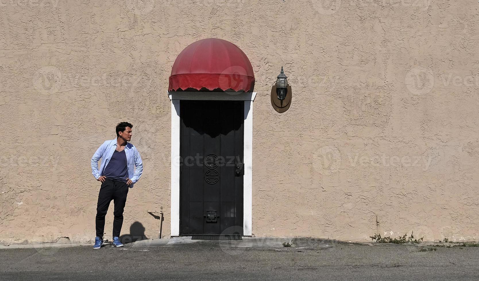 Man standing next to a metal door in the sun photo